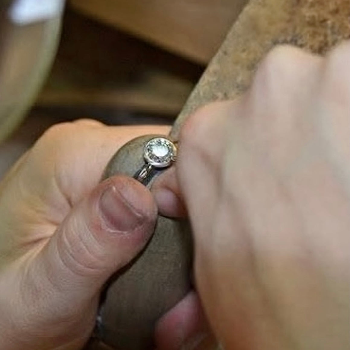 Close-up of a hand holding a hidden ashes memorial ring with a blurred background