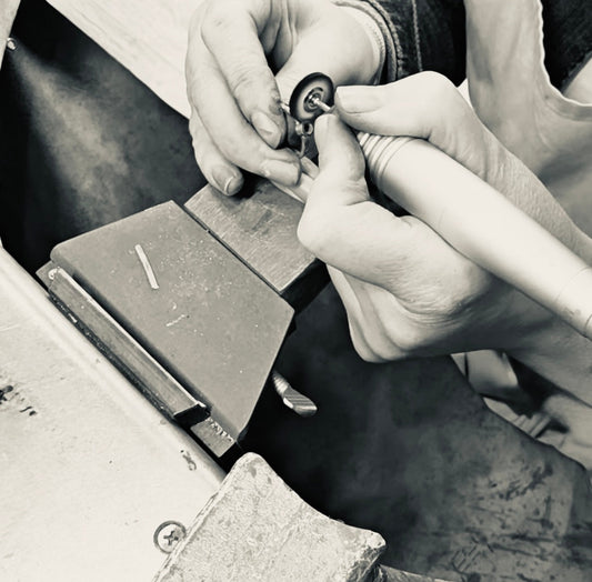 Handcrafted jewellery being shaped on a workbench using traditional silversmithing tools, showing close-up detail of artisan craftsmanship.