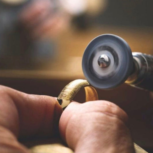 Close-up of a jeweller polishing a gold ring with a rotary tool, highlighting the handmade finishing process and fine craftsmanship.