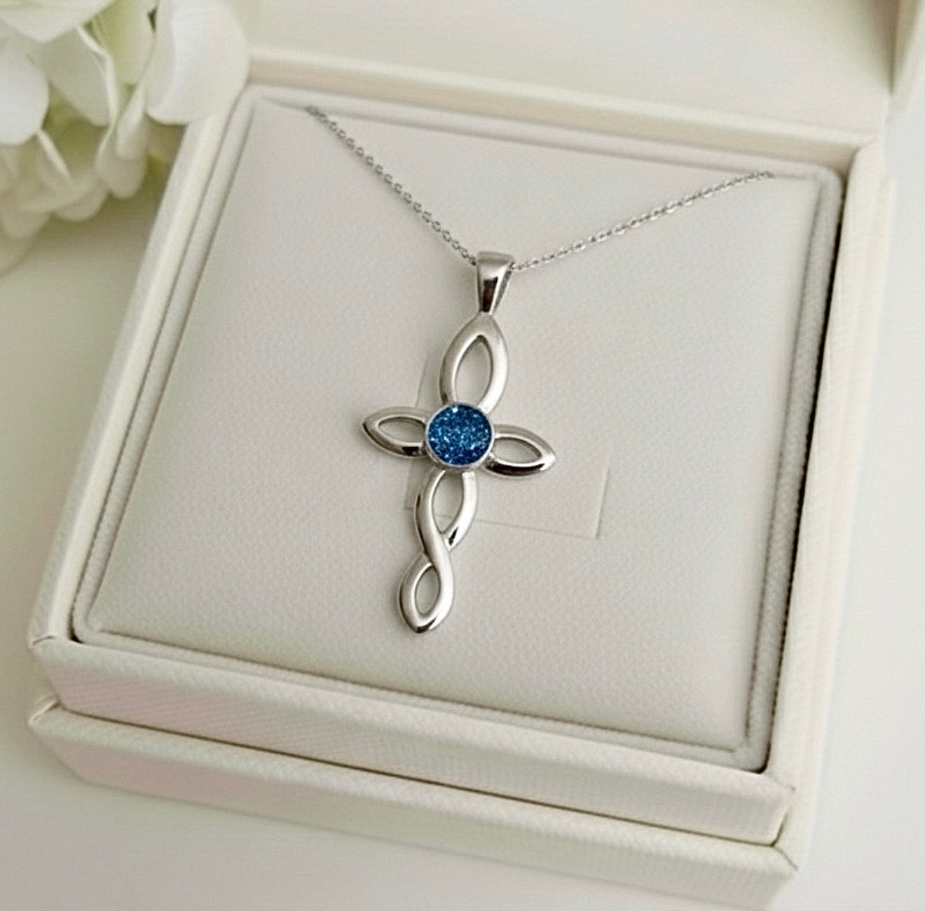 Silver cross ashes keepsake pendant with blue gemstone in a white Memory Within jewelry box