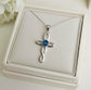 Silver cross ashes keepsake pendant with blue gemstone in a white Memory Within jewelry box