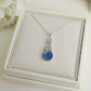 Silver necklace with a blue celtic ashes keepsake pendant on a white memory within jewelry box