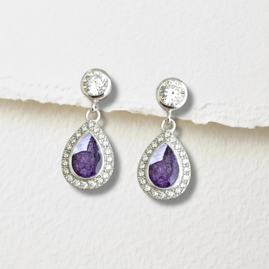 Teardrop-shaped ashes keepsake earrings with purple stones and clear crystals on a white background