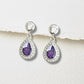 Teardrop-shaped ashes keepsake earrings with purple stones and clear crystals on a white background