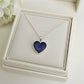 Heart-shaped purple ashes keepsake pendant necklace in a white memory within jewelry box with white flowers in the background