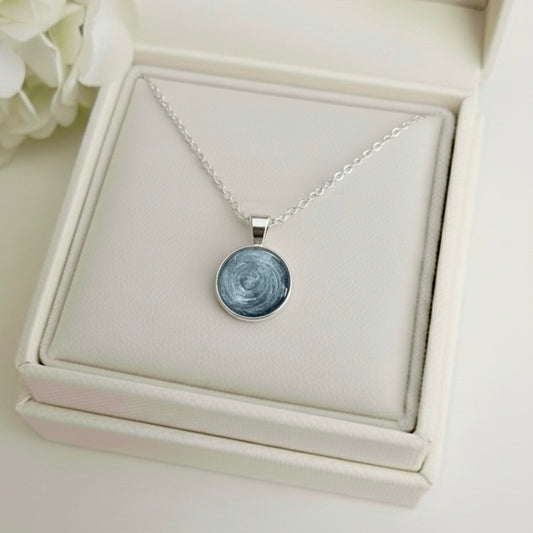 Necklace with a round ashes keepsake pendant on a white memory within jewelry box