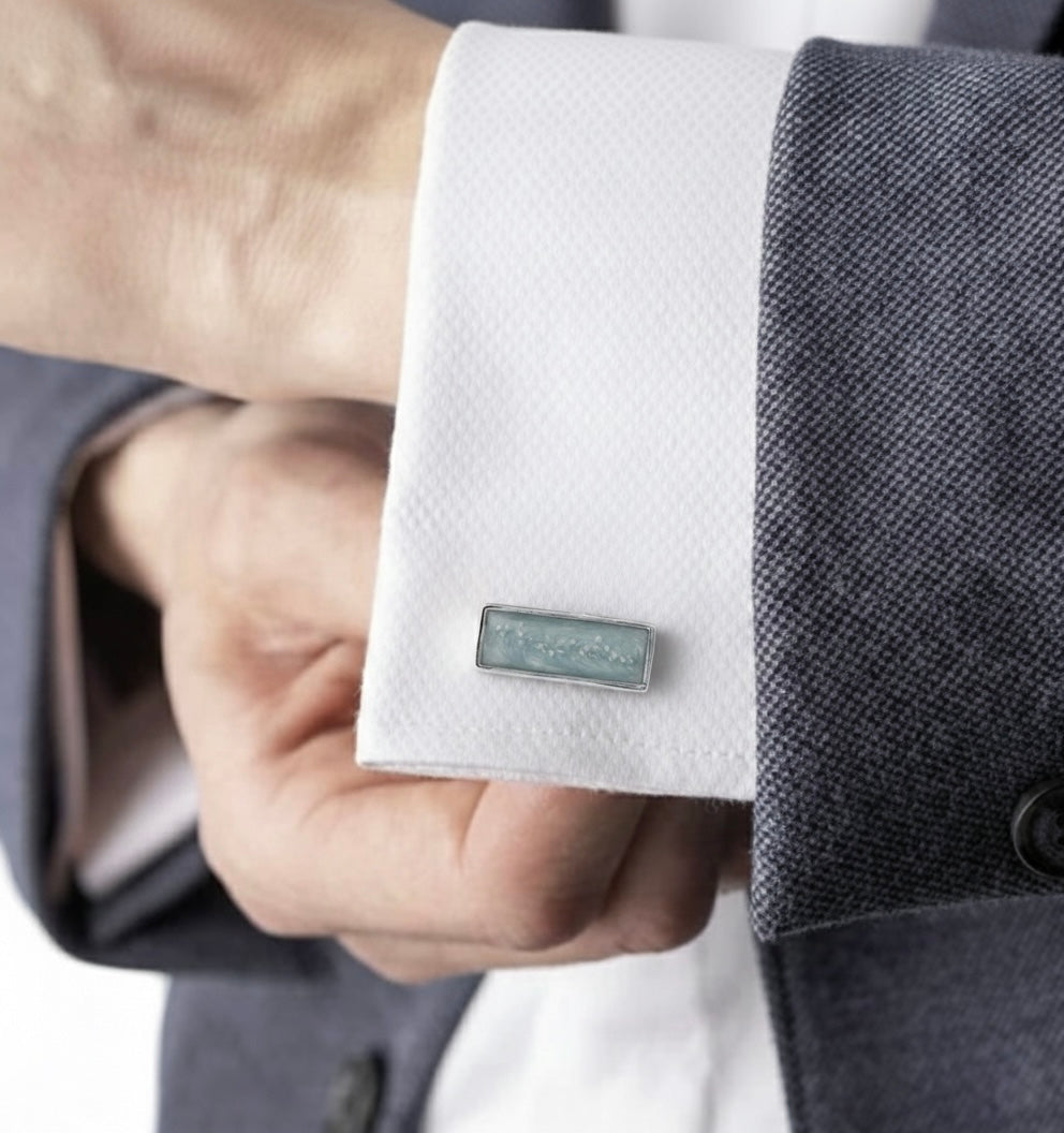 Close-up of a person wearing a gray suit with an ashes Eros Memory Within cufflink on a light background