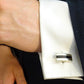 Close-up of a silver Memory Within Eros Bar ashes cufflink on a white cuff against a dark suit background