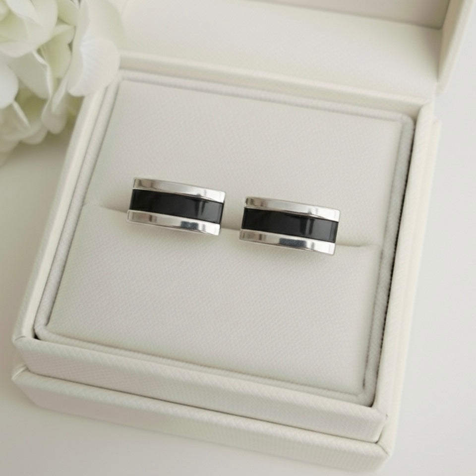 Silver ashes cufflinks with black accents on a white memory within jewelry box