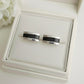 Silver ashes cufflinks with black accents on a white memory within jewelry box