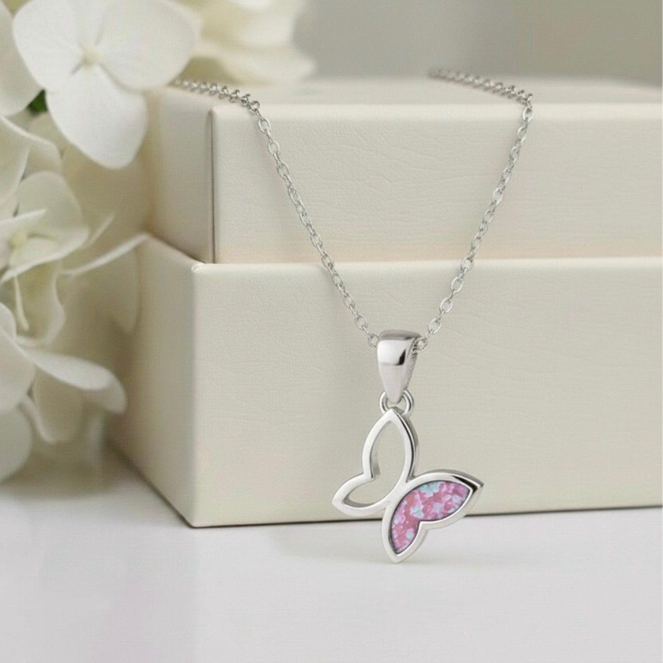 Butterfly-shaped necklace with pink center on a white background