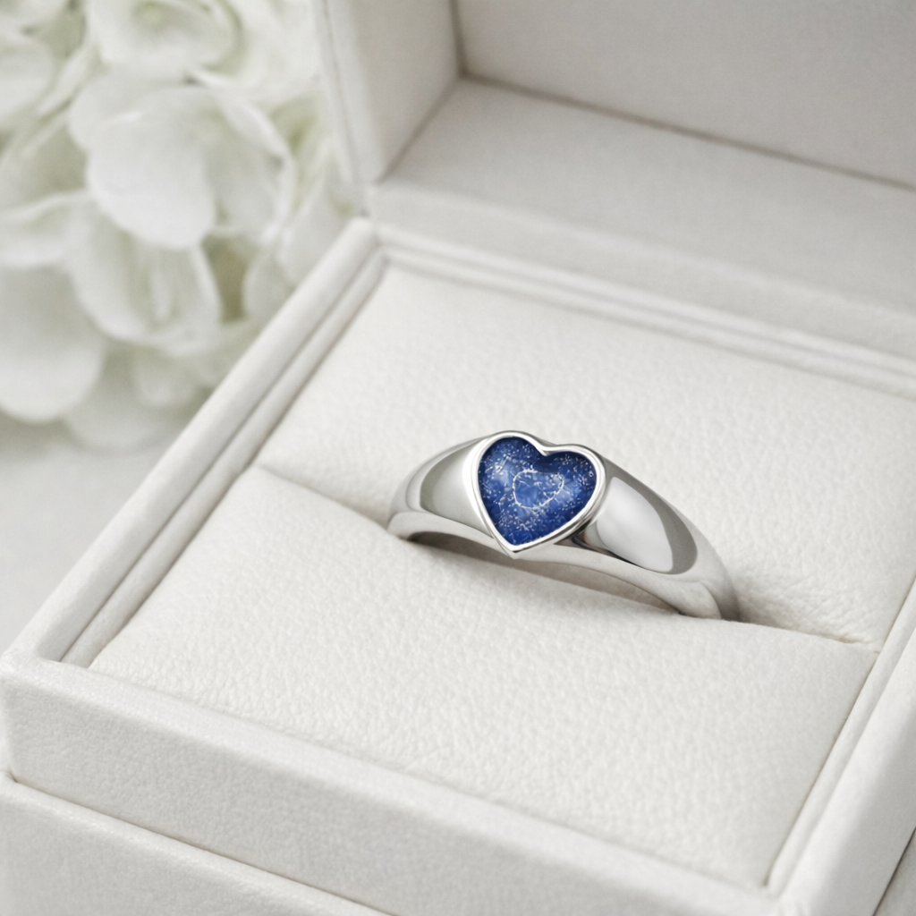 Silver ring with a blue heart ashes keepsake stone in a white memory within jewelry box.