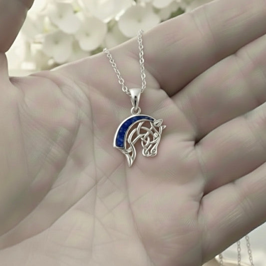 Silver horse ashes keepsake pendant necklace held in a hand with a blurred floral background