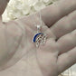 Silver horse ashes keepsake pendant necklace held in a hand with a blurred floral background