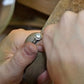 Close-up of a hand holding a hidden ashes memorial ring with a blurred background