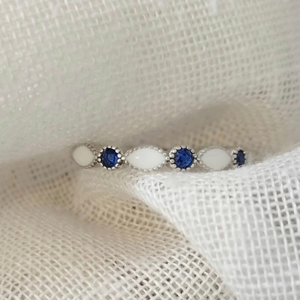 Marquise Gem Halfband breastmilk ring with alternating white breastmilk stones and blue round gemstones.