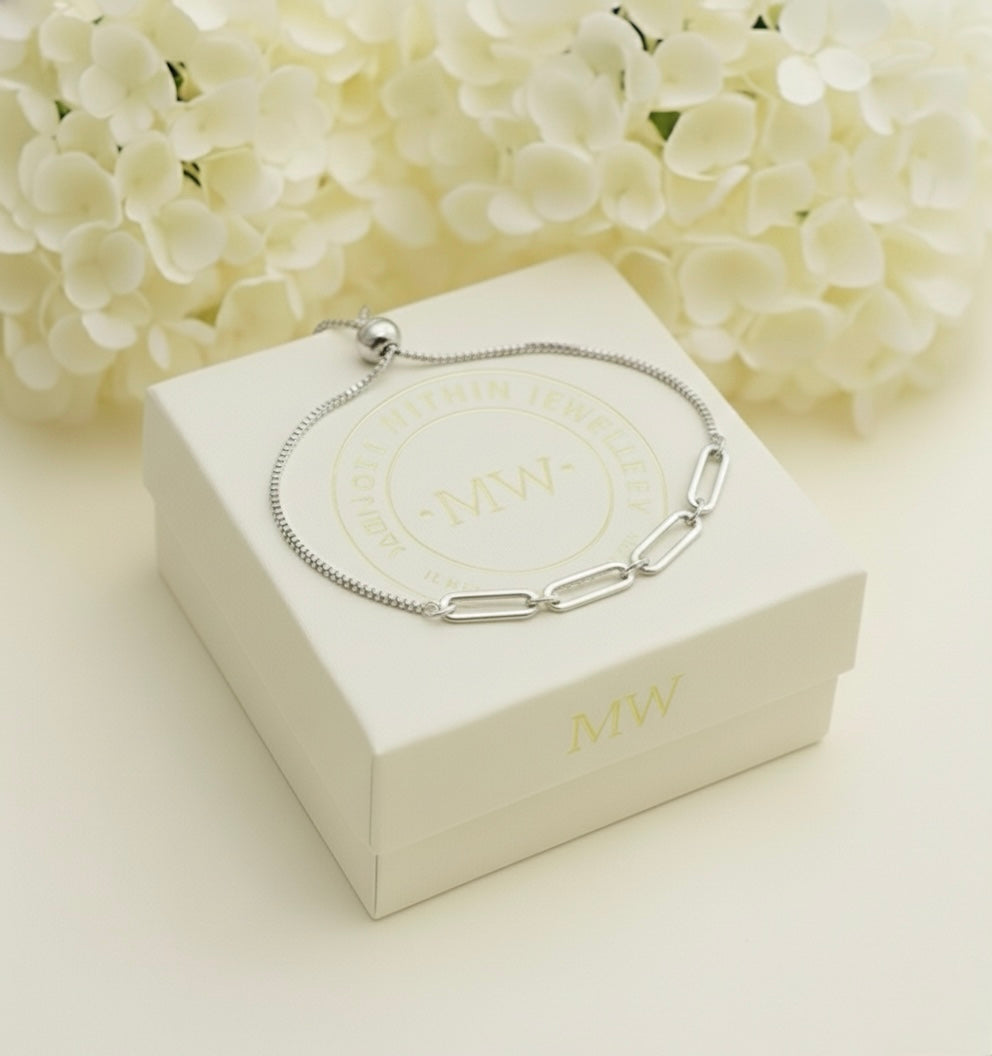 Silver bracelet on a white Memory Within jewelry box with white flowers in the background