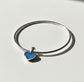 Silver bracelet with a blue heart-shaped ashes keepsake charm on a light gray background