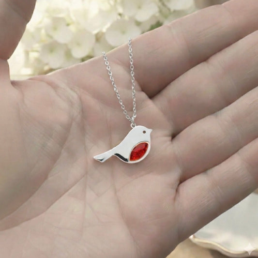 Silver necklace with Robin ashes keepsake memorial pendant held in a hand against a blurred floral background