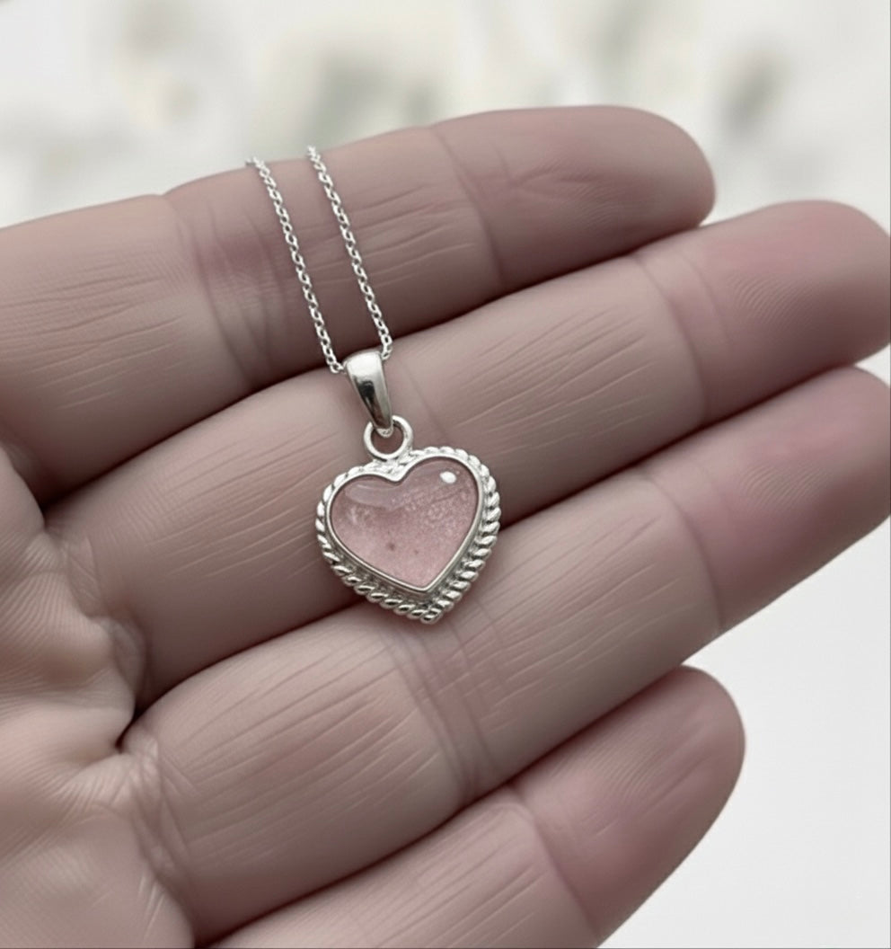 Memory within Heart-shaped silver ashes keepsake pendant on a chain held between fingers