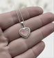 Memory within Heart-shaped silver ashes keepsake pendant on a chain held between fingers